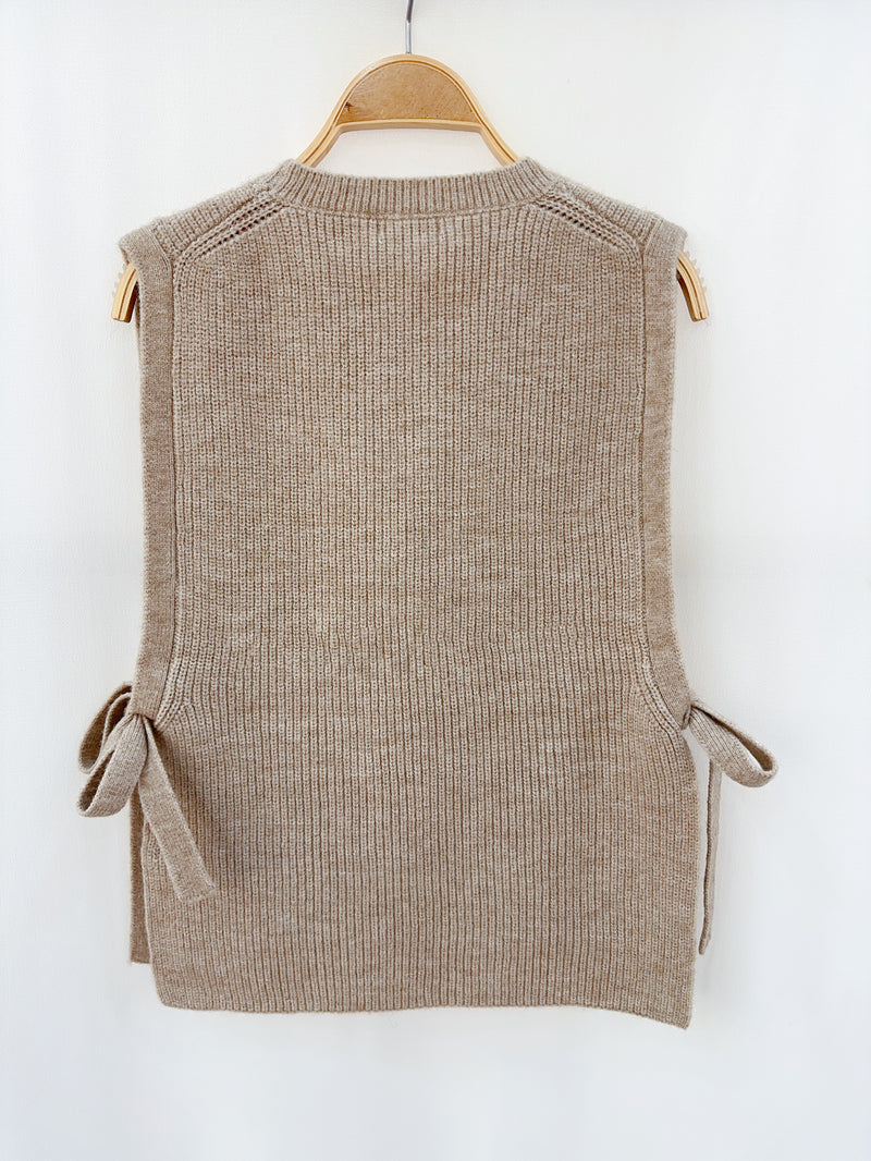 Zachte en comfortabele taupe mouwloze trui met ronde hals en trendy zijstrikken.