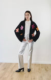 Model draagt een zwart gebreid vest met felle bloemenprints