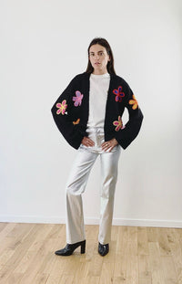 Model draagt een zwart gebreid vest met felle bloemenprints