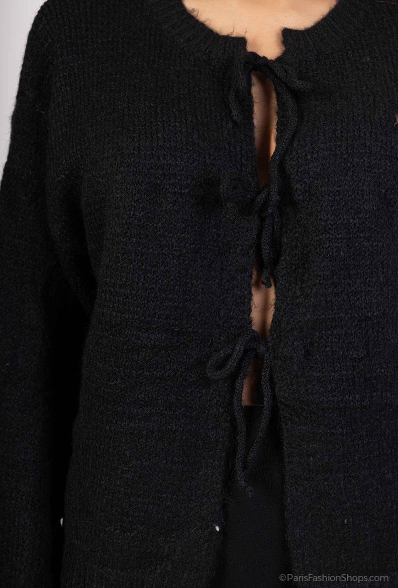 Detail van de strik op de zwarte gebreide trui, een trendy en stijlvolle touch voor een verfijnde uitstraling.